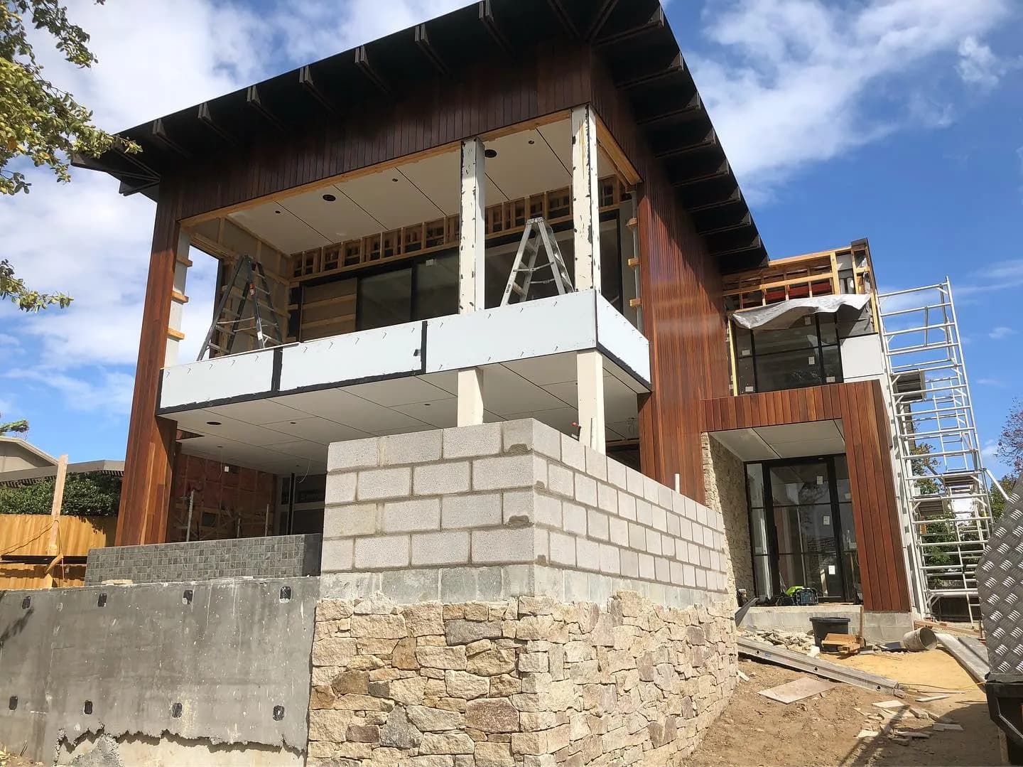 Architectural home with random-coursed sandstone base and timber cladding