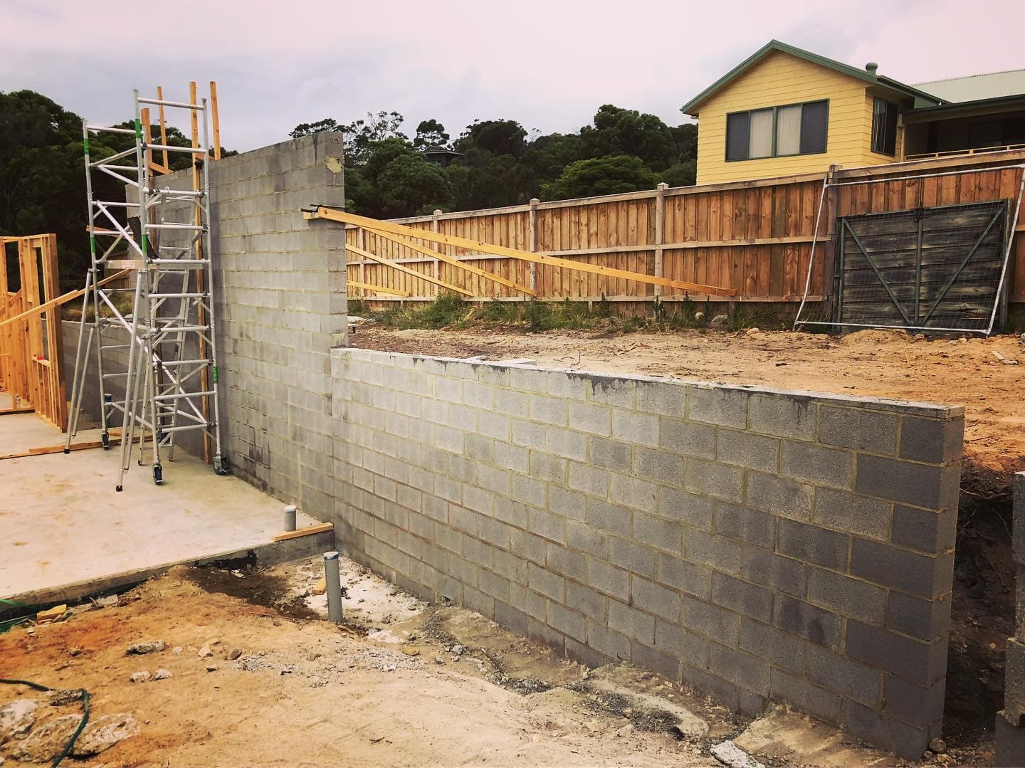 Long grey block boundary wall in front of weatherboard home